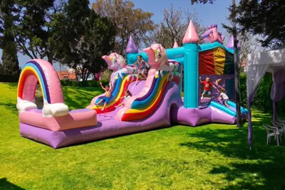 Niños jugando en un brincolín inflable de princesas durante una fiesta infantil.