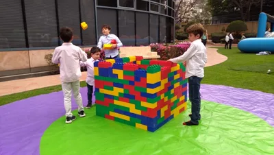 Alumnos de secundaria cruzando una pista de obstáculos inflable dentro de la alberca de su escuela, con sus compañeros animando desde la orilla.